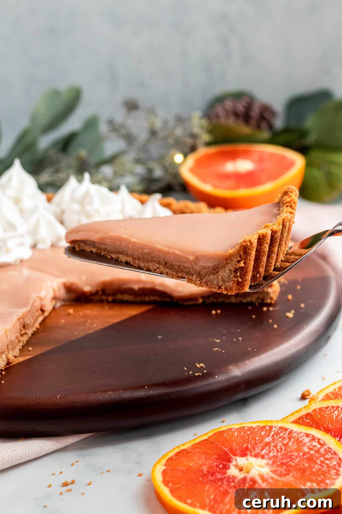 Zesty Blood Orange Tart Recipe with Buttery Shortcrust 3 a slice of blood orange tart is being lifting from the whole tart on a serving spatula