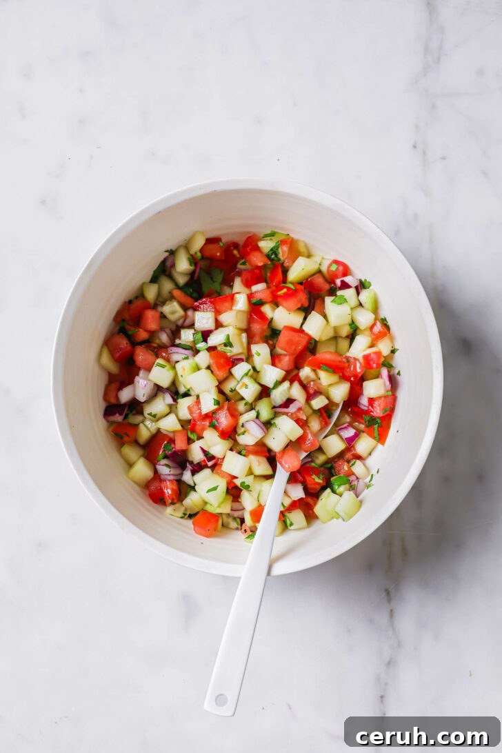 Kachumber Salad in a white bowl with a white spoon.