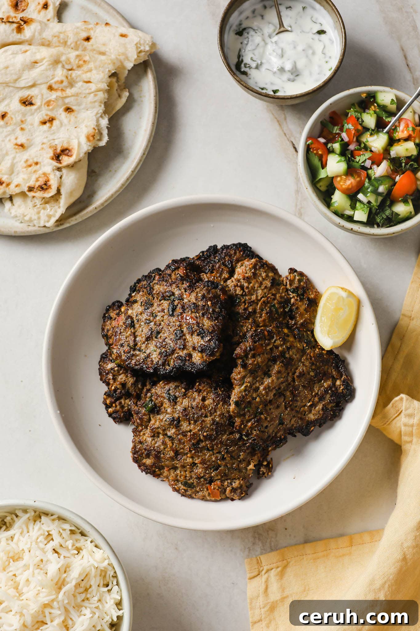 A plate with Chapli Kabab served with naan, raita, salad, and rice.