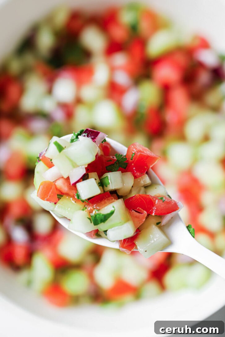 Holding some Kachumber Salad in a white spoon.