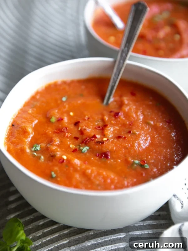 White soup bowl filled with homemade tomato basil soup.