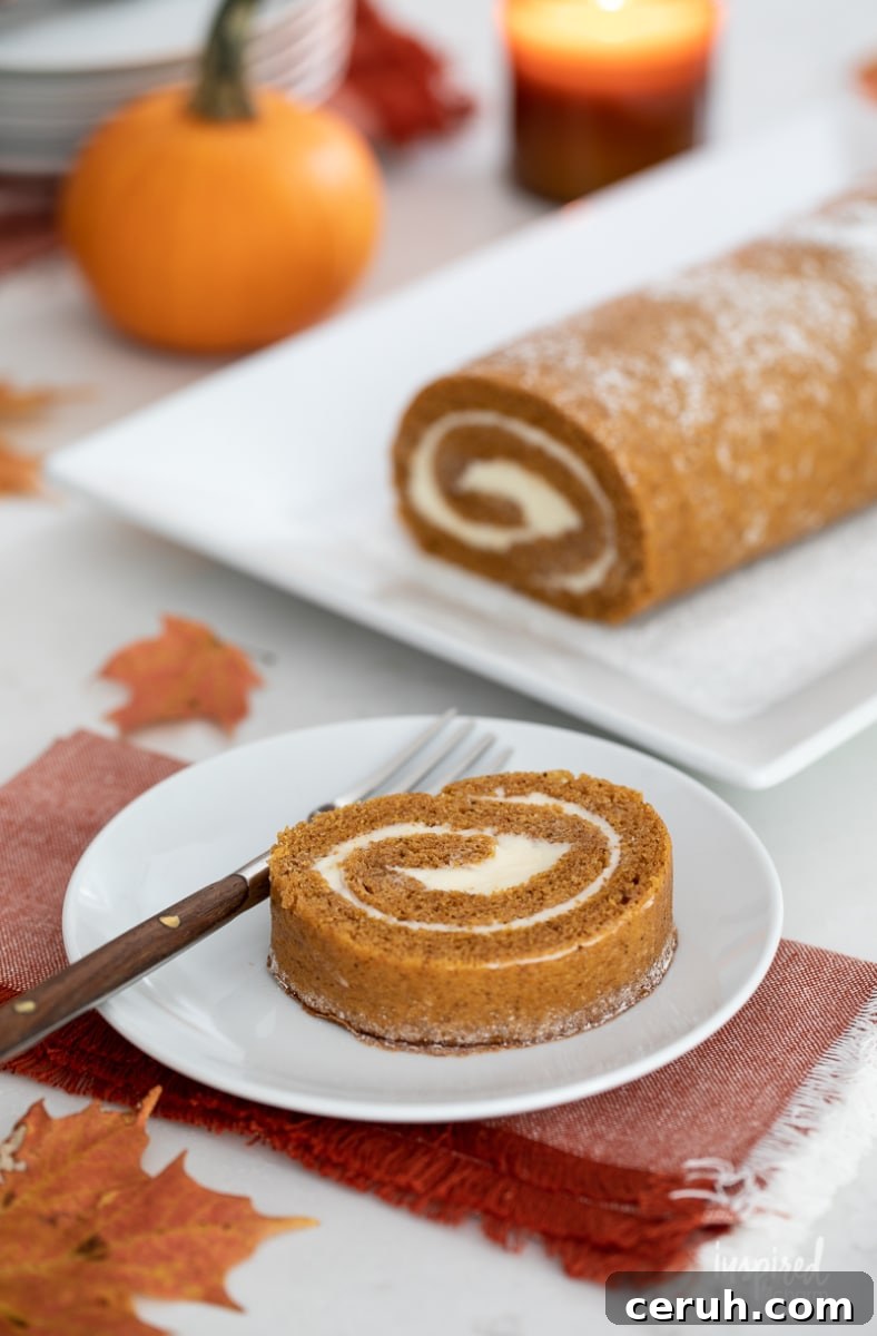 slice of pumpkin roll on a plate with a fork with more in the background.