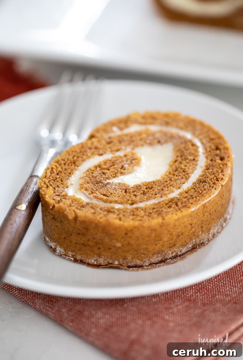pumpkin roll slice on a white plate with a fork.