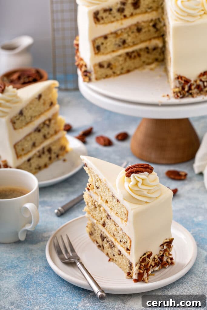 Slices of layered vanilla cake studded with buttered pecans frosted with cream cheese frosting on a white plate