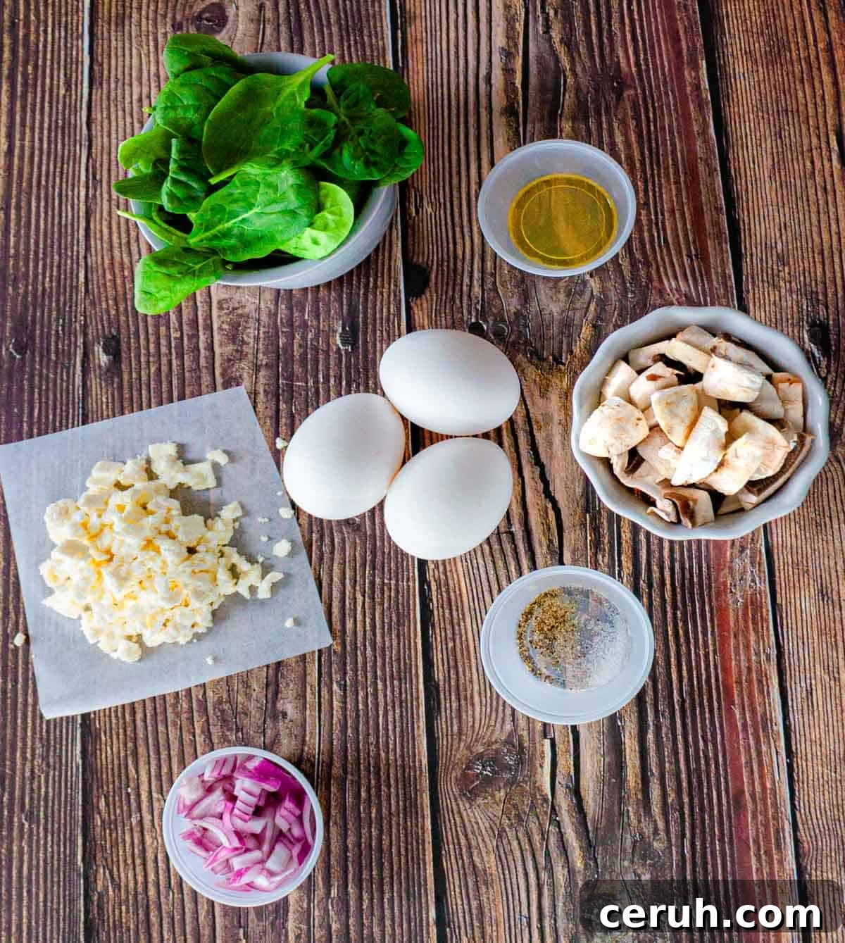 Ingredients for the spinach omelette measured out and placed on a wooden table.