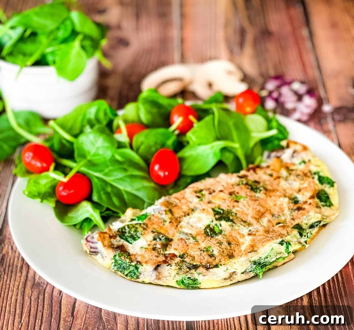 The omelette on a white plate with a salad.