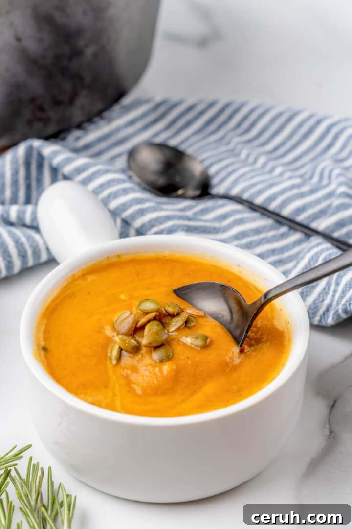 butternut squash soup in white bowl with spoon.