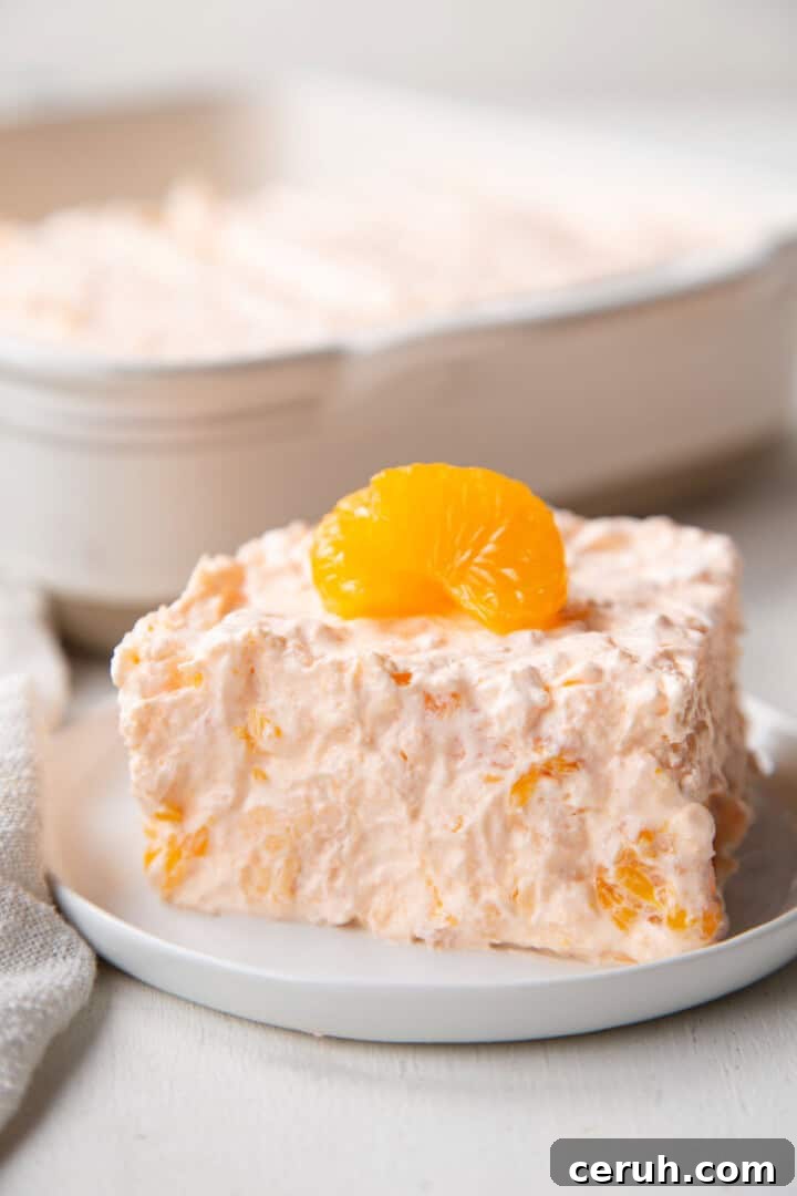 slice of orange gelatin salad with mandarin oranges inside and on top.