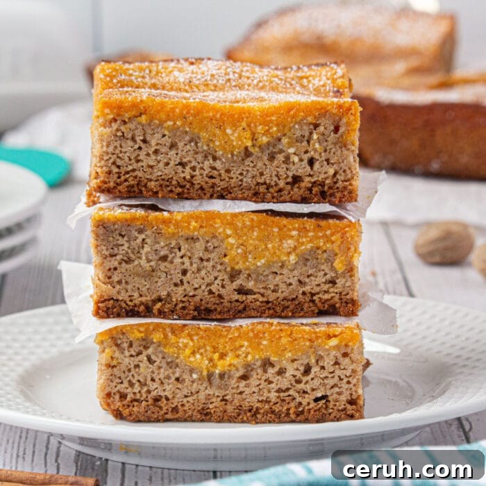 A stack of pumpkin bars on a plate showing the layers of spice cake and pumpkin.
