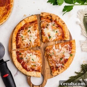 Cheesy pizza with a golden crust of pita bread on a cutting board on a marble table.