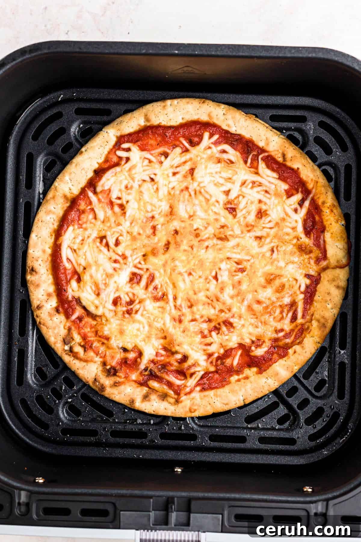 Crispy pita pizza with golden brown crust in the air fryer basket. 