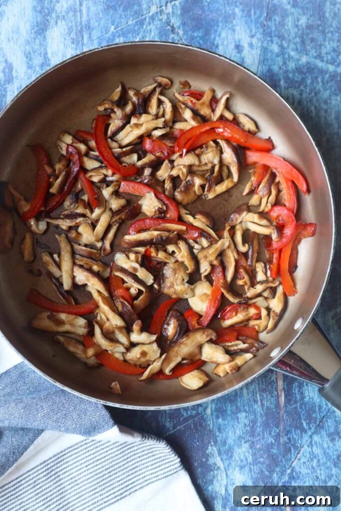 skillet with sautéed chopped red bell pepper and mushrooms