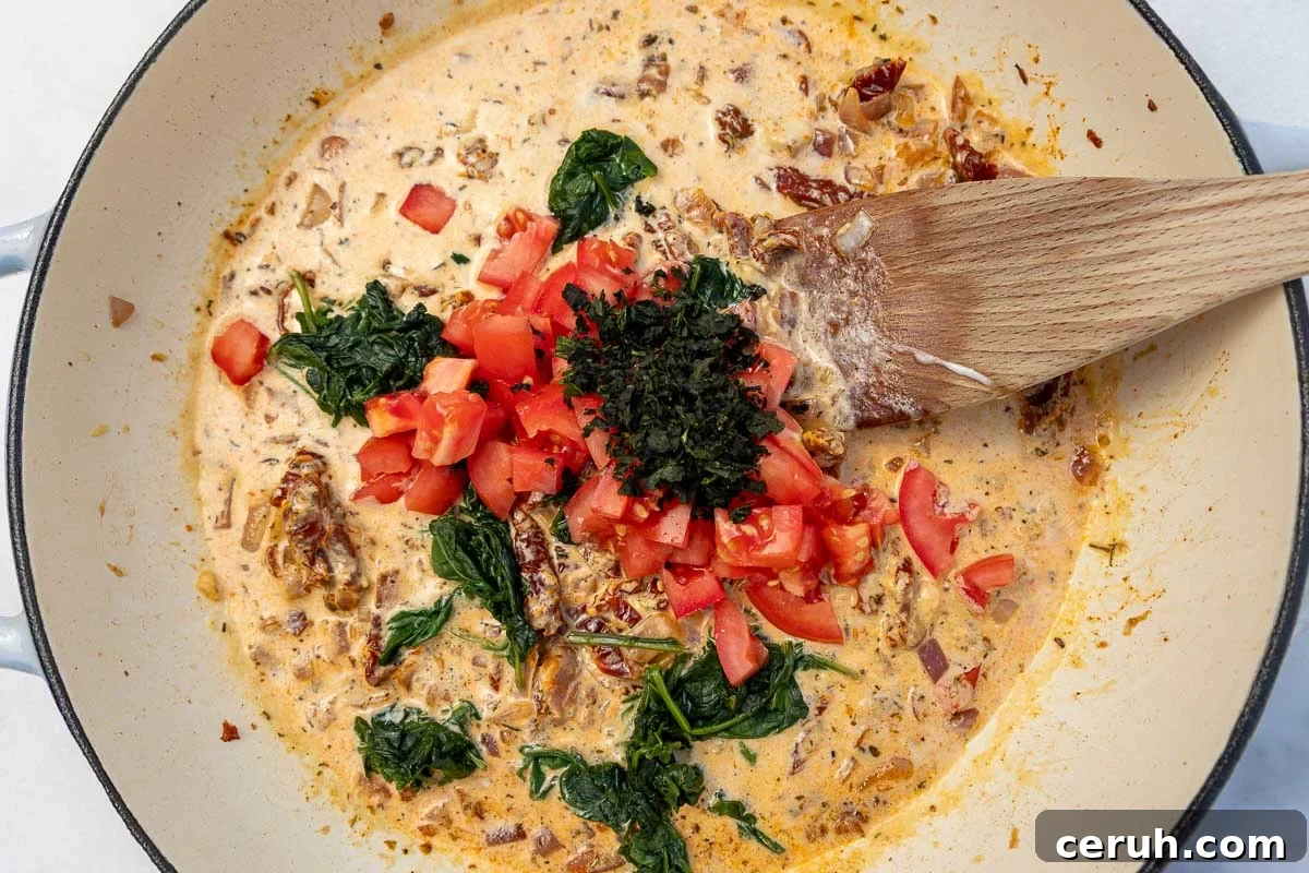Overhead of ingredients for the sauce in a large cast iron pan with a wooden spoon.