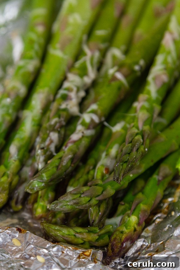 close up of cooked asparagus on foil with Parmesan cheese