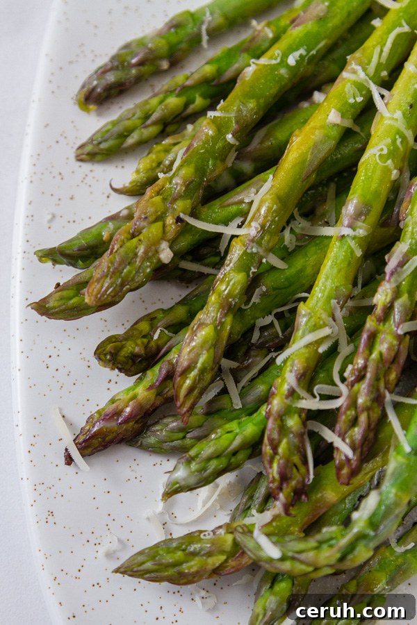 grilled asparagus arranged on a white platter topped with Parmesan