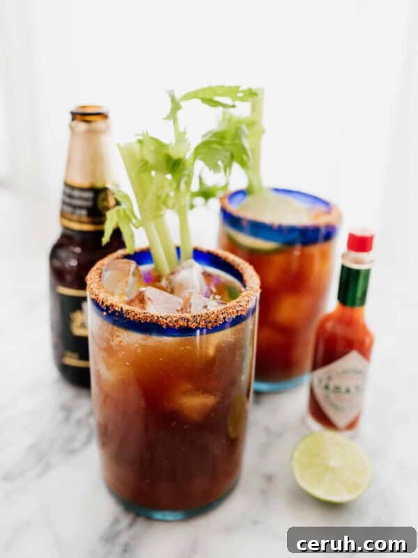 two Michelada beer cocktails with a beer and tabasco on the side
