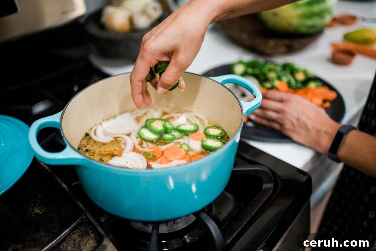 woman making Mexican escabeche in an aqua-colored enameled Dutch oven.