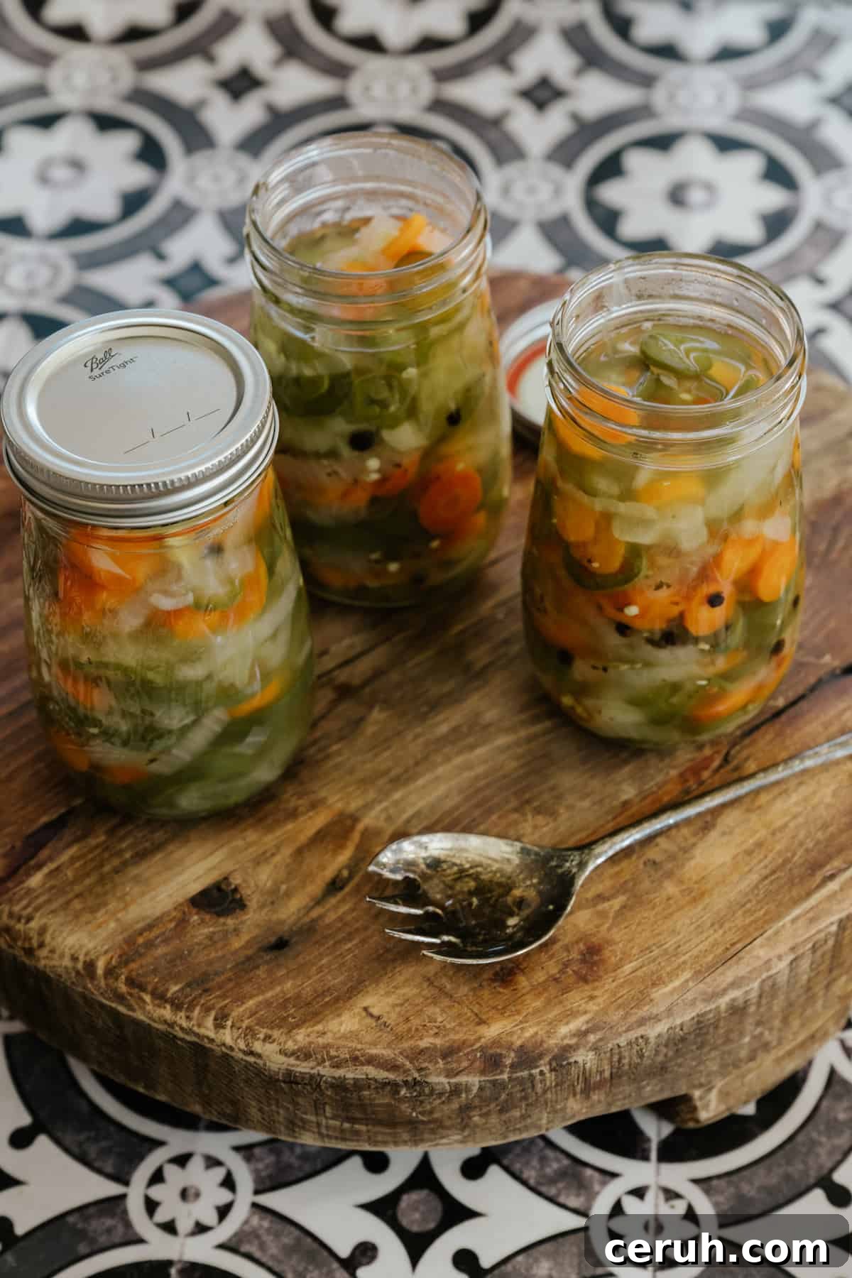 45 degree angle of jars of Mexican escabeche lined up on a wooden surface.