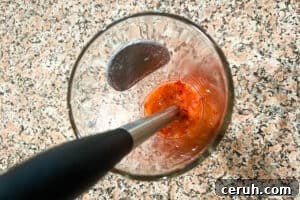 Strawberries and maple syrup being mashed into puree with muddler