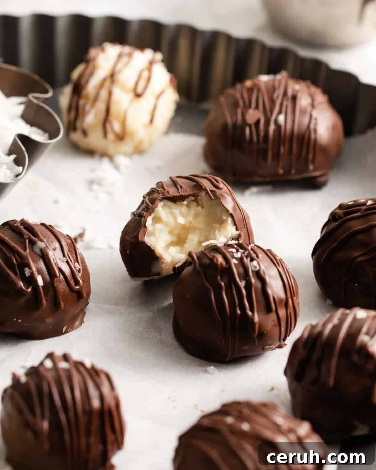 a bitten coconut truffle on a serving dish full of coconut truffles.