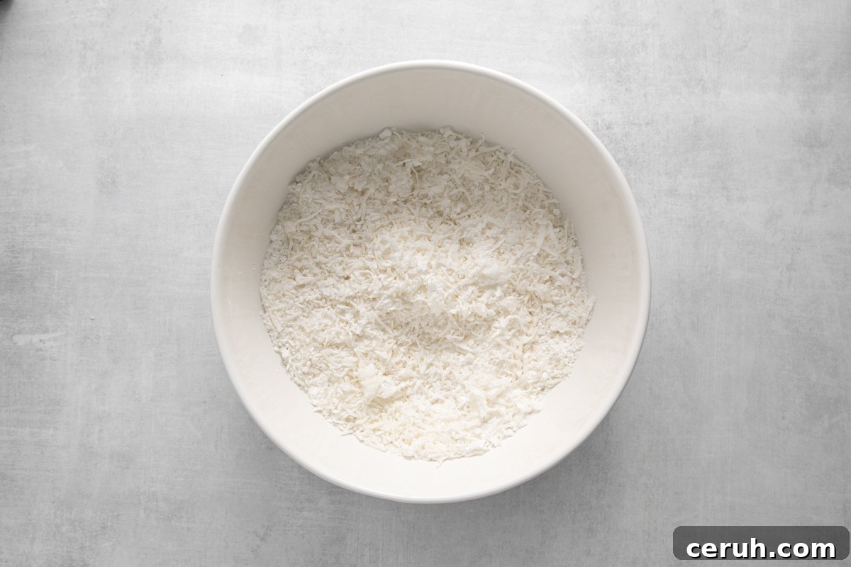 shredded coconut mixed with powdered sugar in a white bowl.
