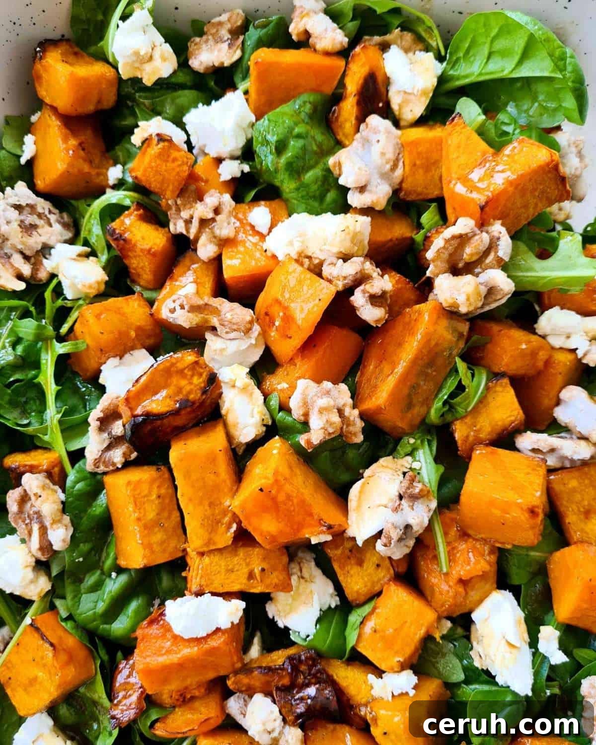 Close up of a large serving dish of pumpkin salad with lots of walnuts and pumpkin