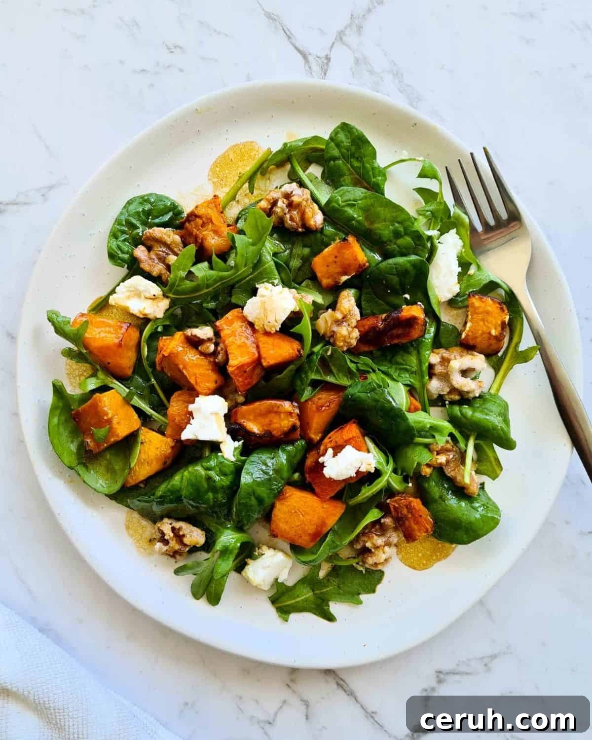 Overhead view of salad on a white plate with a fork 