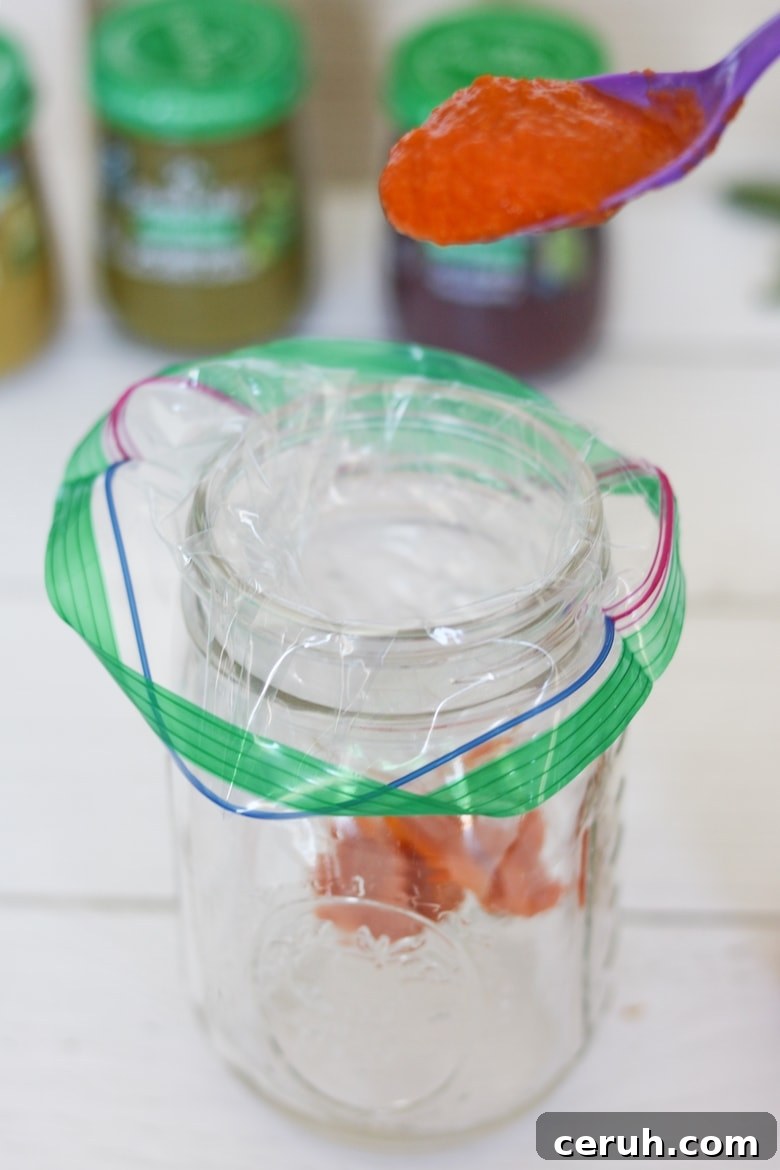 sandwich baggie in mason jar, being filled with an orange baby food puree.