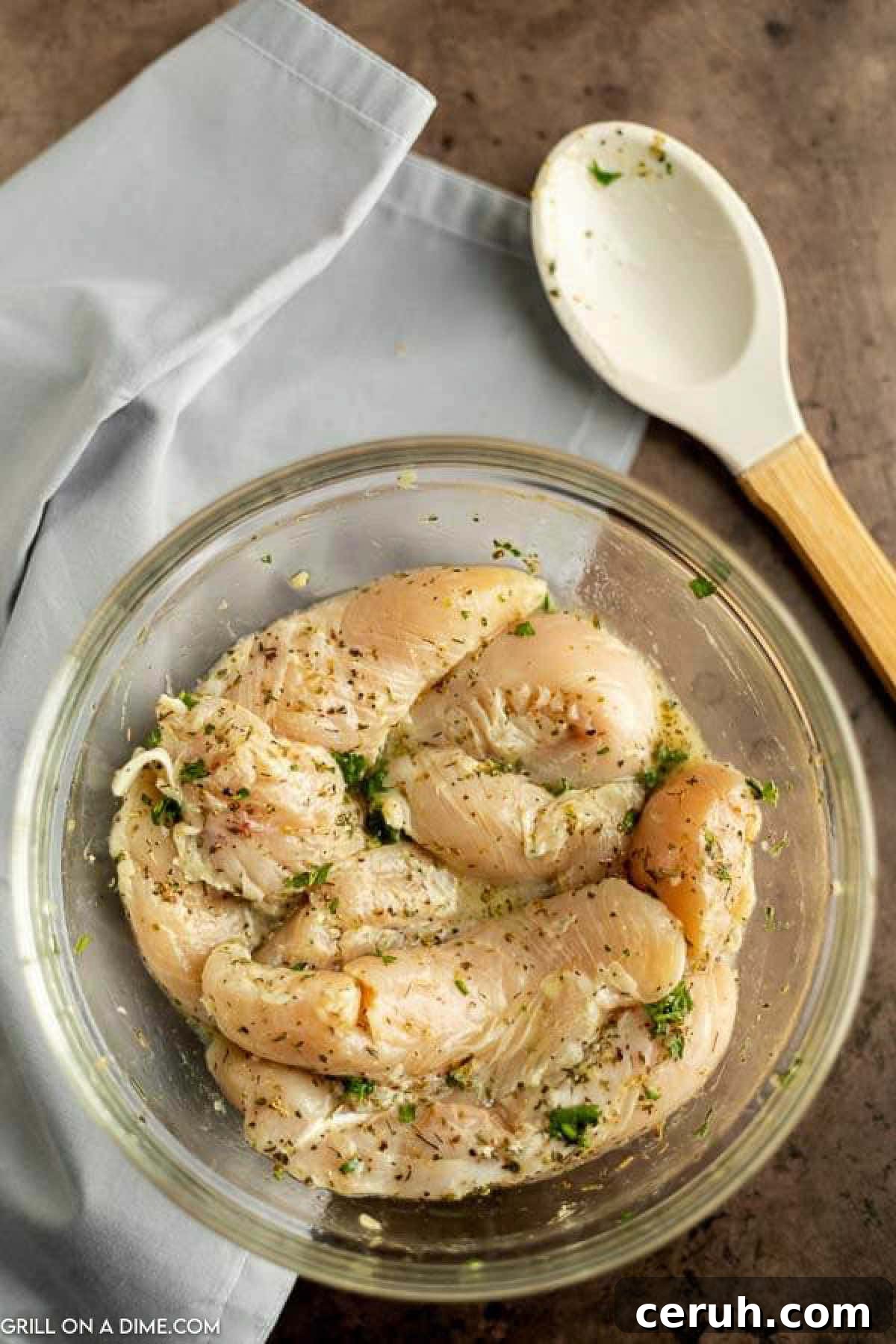 Raw chicken tenders in a bowl with seasoning. 