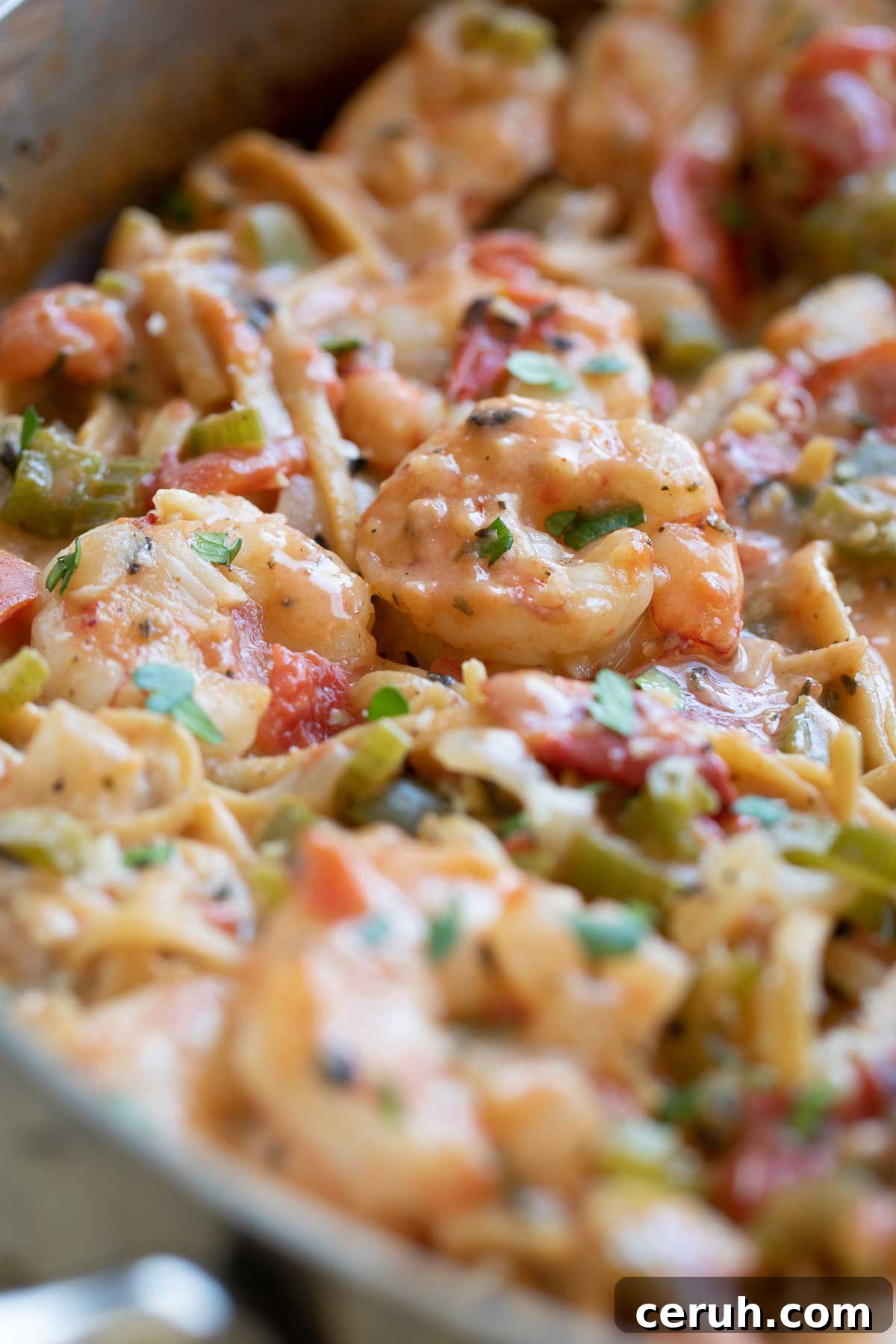 Closeup of the shrimp, still in the pan, sitting on top of the pasta and dotted with creamy sauce and bits of parsley.