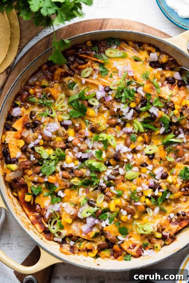 Vegetarian Enchilada casserole in a yellow skillet on a white wooden table.