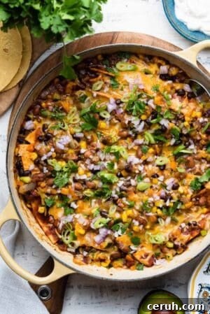 Vegetarian Enchilada casserole in a yellow skillet on a white wooden table.