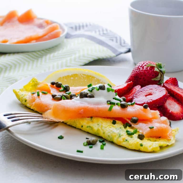 A smoked salmon omelette with creme fraiche on a plate with fresh fruit.