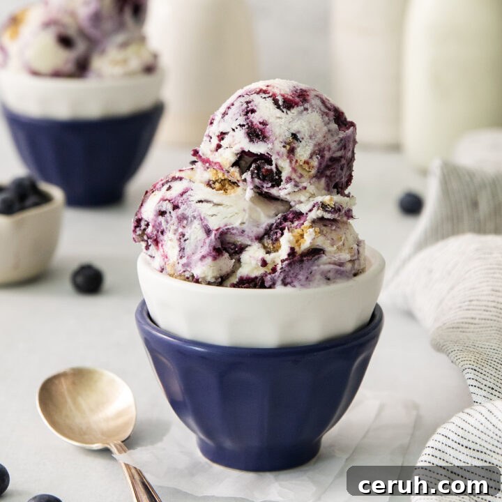 scoops of blueberry cheesecake ice cream in a blue ceramic bowl.