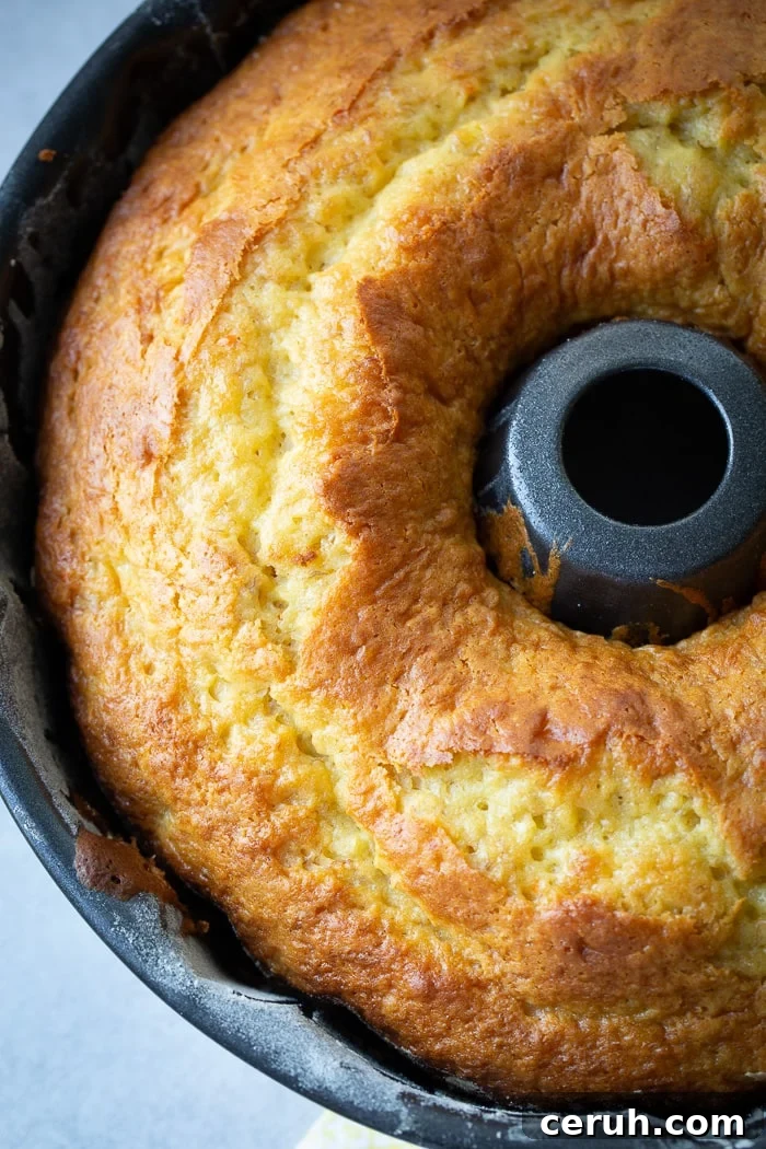 A dark bundt pan with a beautiful, bright yellow banana pudding bundt cake 