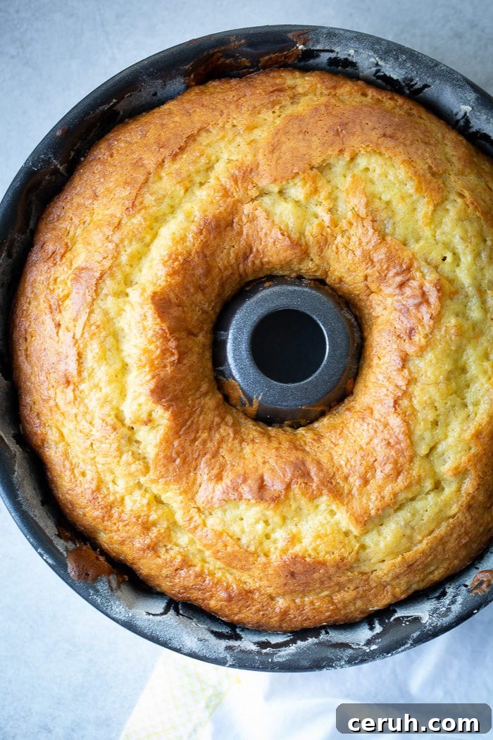 A dark bundt pan with a beautiful, bright yellow banana pudding bundt cake
