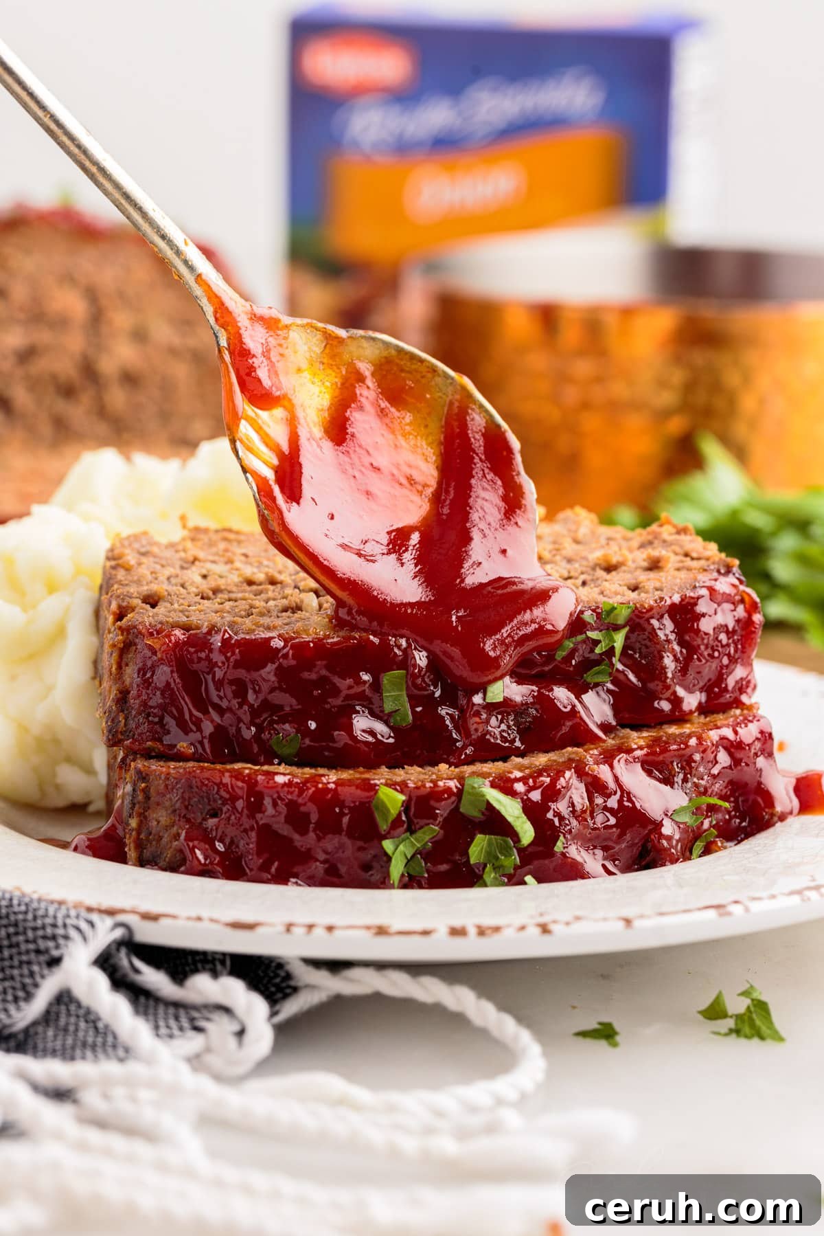 Sauce drizzled on Lipton Onion Soup Meatloaf slices on a plate with a spoon.