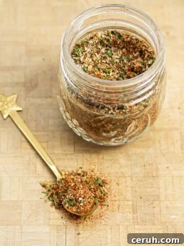A jar of breakfast sausage seasoning with a spoonful of the mix scooped out.