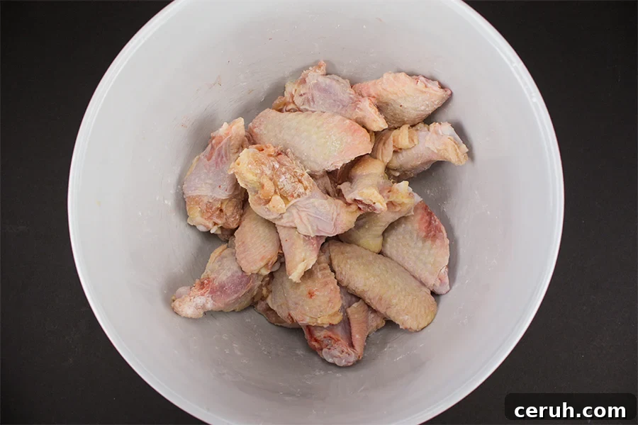 Raw wings coated in baking powder and salt in a white bowl.