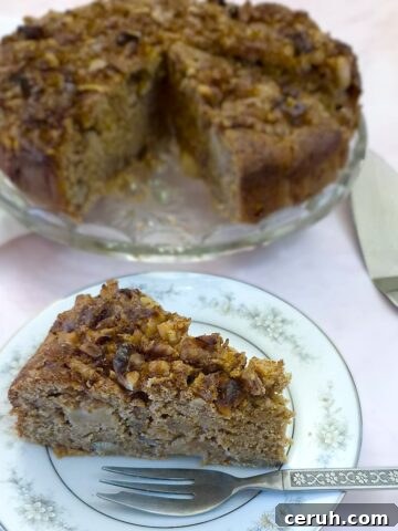 A slice of easy apple and chestnut cake on a plate, showing the walnut and cinnamon sugar topping.
