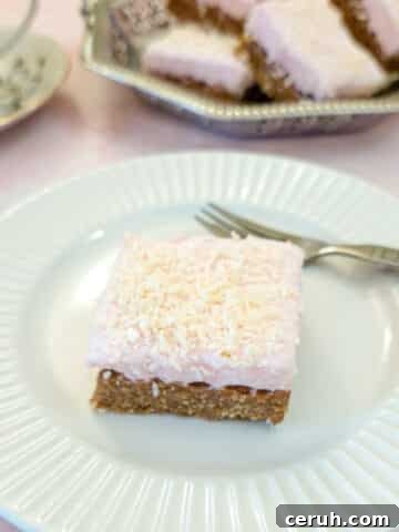 A sqiuare piece of coconut marshmallow wee-bix slice on a whte plate.