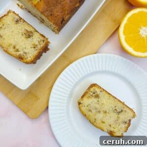 Orange Walnut Drizzle Cake with Zesty Citrus Glaze 16 A slice of orange walnut drizzle cake on a small white plate, next to another slice cut from the cake on a white platter.