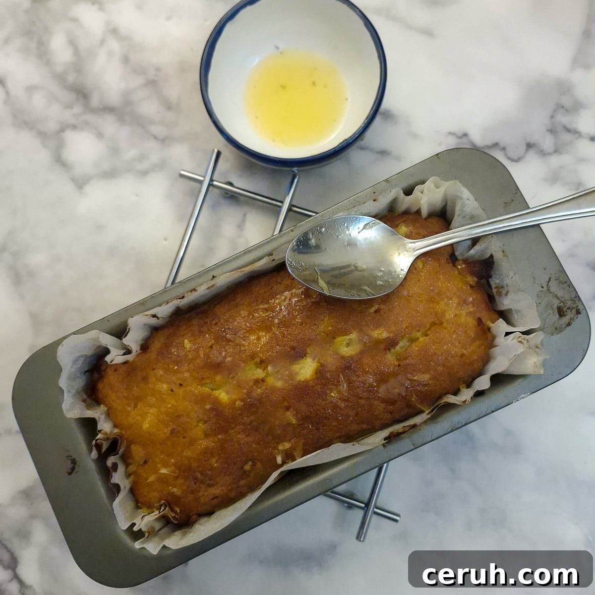 Orange Walnut Drizzle Cake with Zesty Citrus Glaze 10 Step 6, orange drizzle being spooned over the baked orange cake.