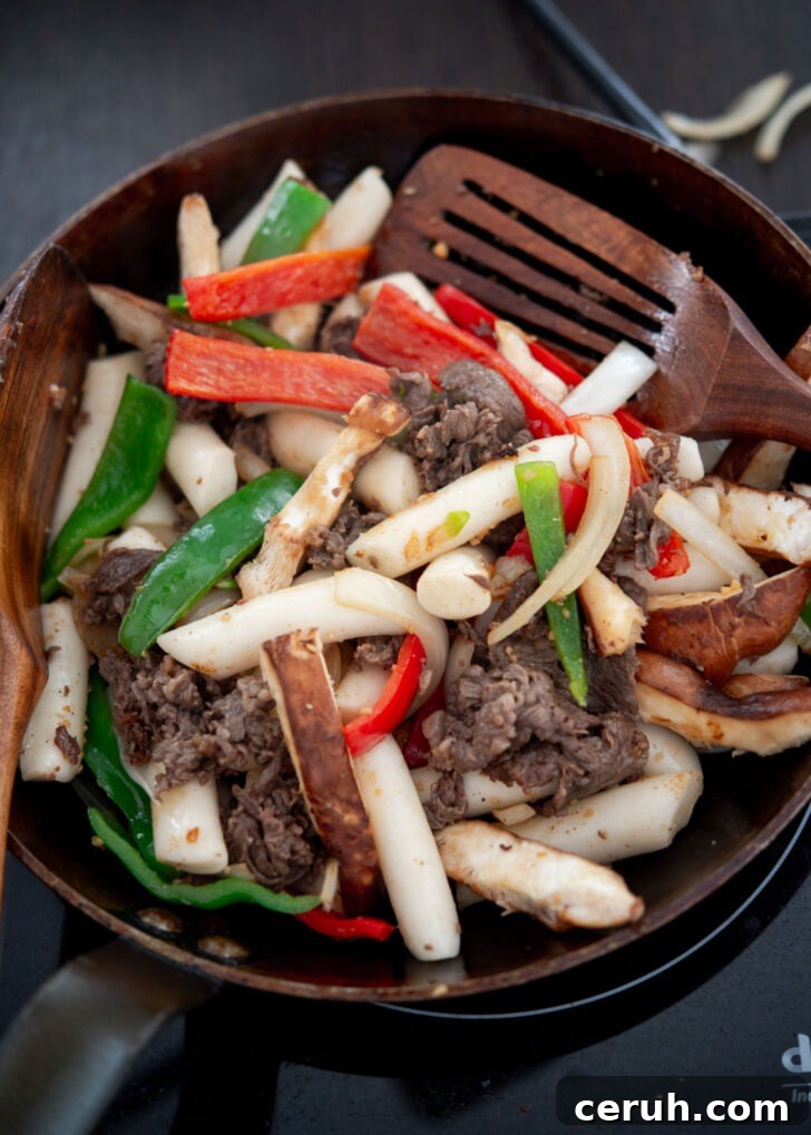 Adding rice cakes to the beef and vegetable stir-fry.