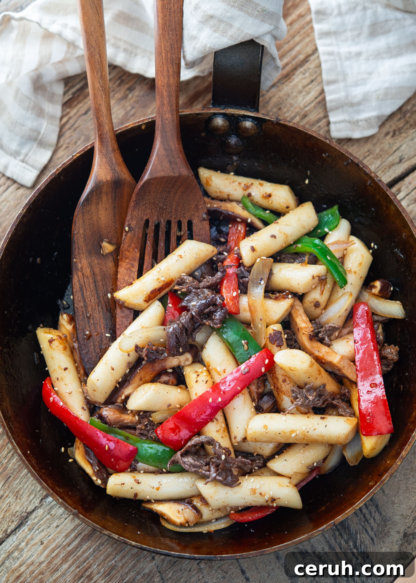 Stir-fried rice cakes with beef and vegetables in a skillet.