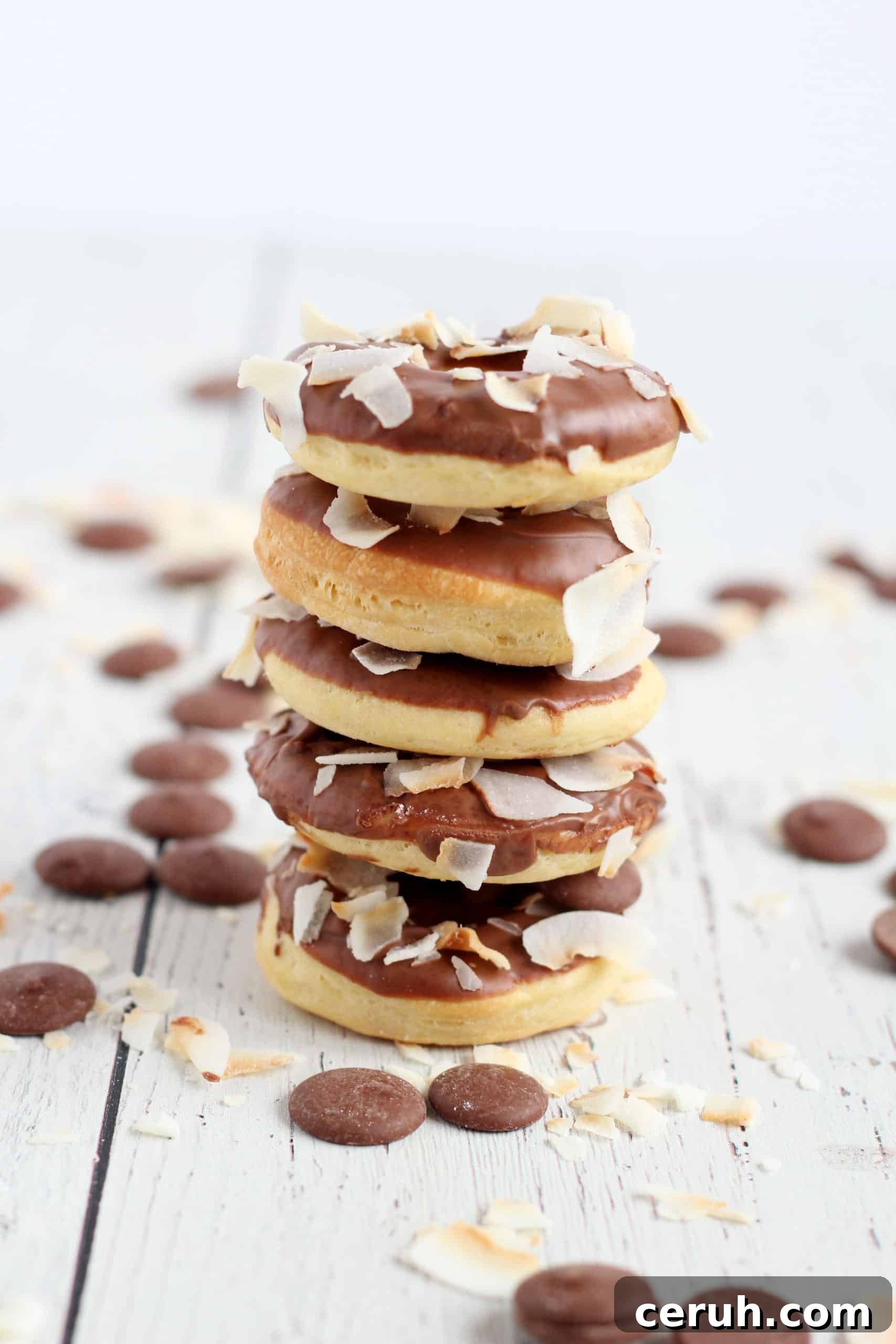 five baked donuts glazed with chocolate stacked on each other