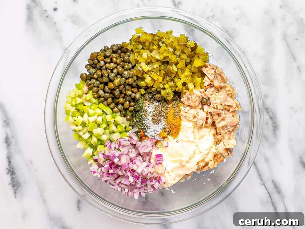 Large bowl filled with ingredients to make tuna salad.