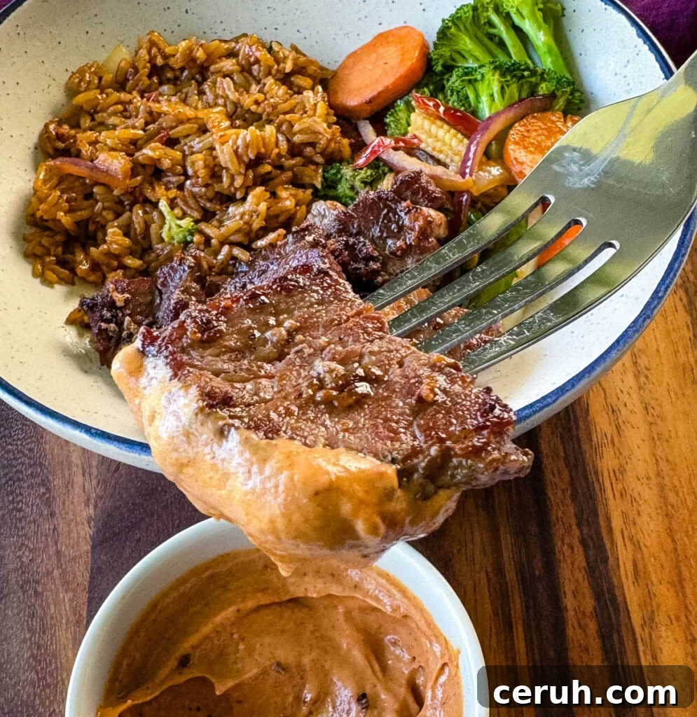 Hibachi Steak with Garlic Fried Rice Recipe 13 a fork dipped with steak and sauce over a hibachi bowl