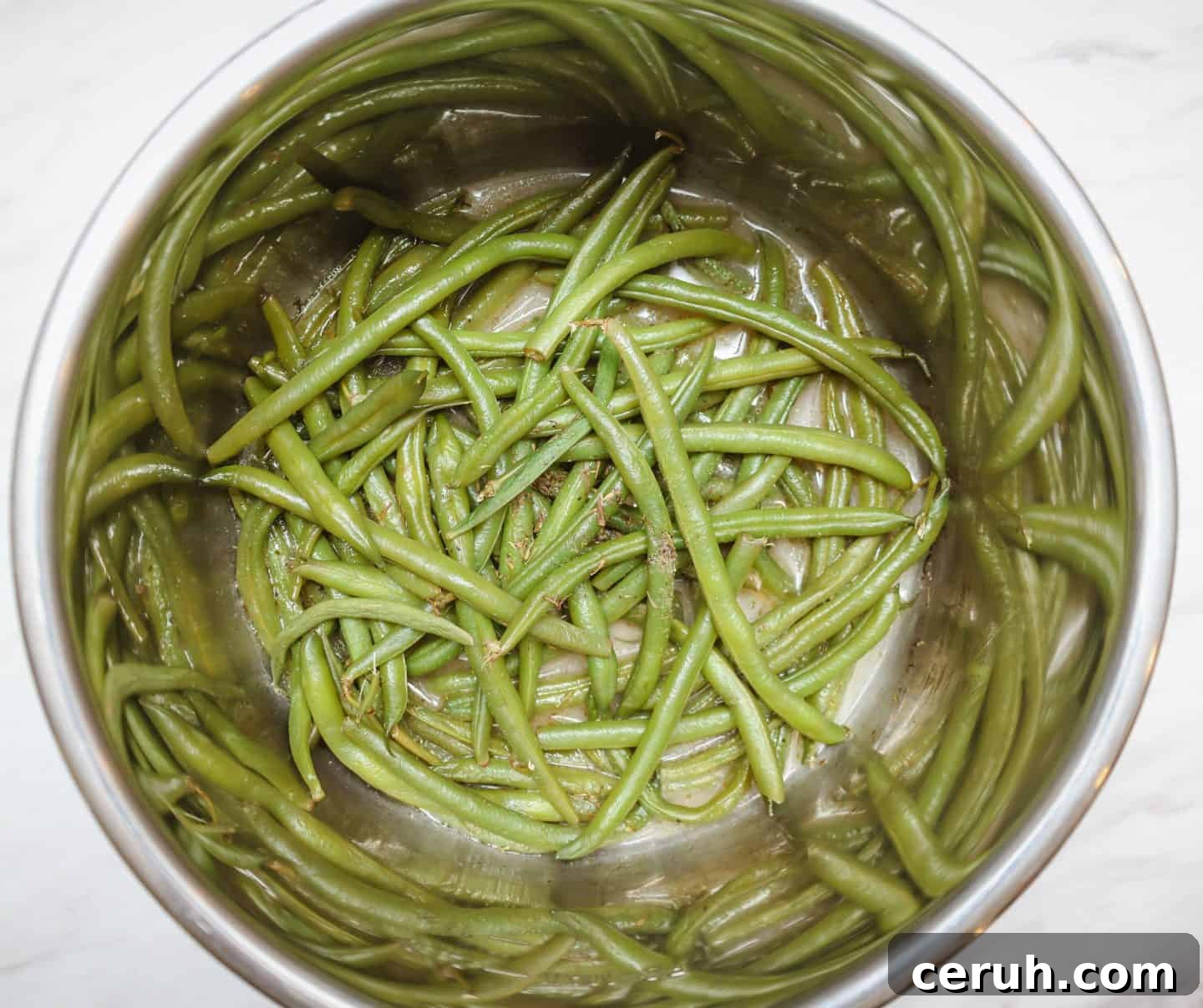 Finished green beans inside an Instant Pot inner pot with seasoned broth, preparing Instant Pot soul food green beans the modern Southern way by Shaunda Necole of The Soul Food Pot®.