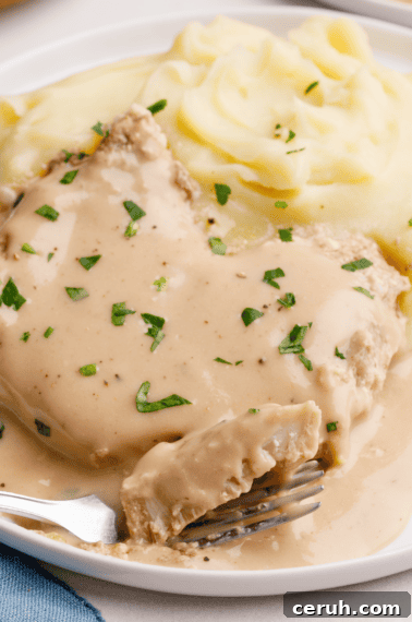 crockpot porkchops on a plate with mashed potatoes and gravy